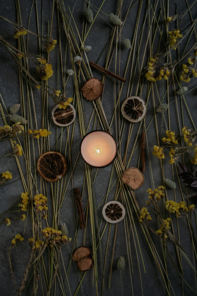 A candle surrounded by dried flowers and herbs
